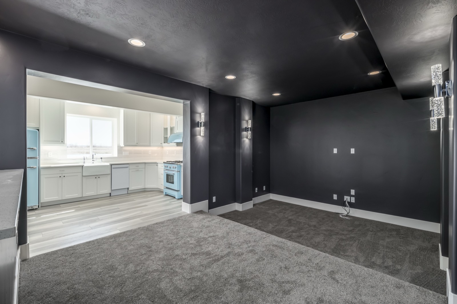 Basement apartment kitchen with white cabinets and retro blue appliances next to a charcoal accent wall