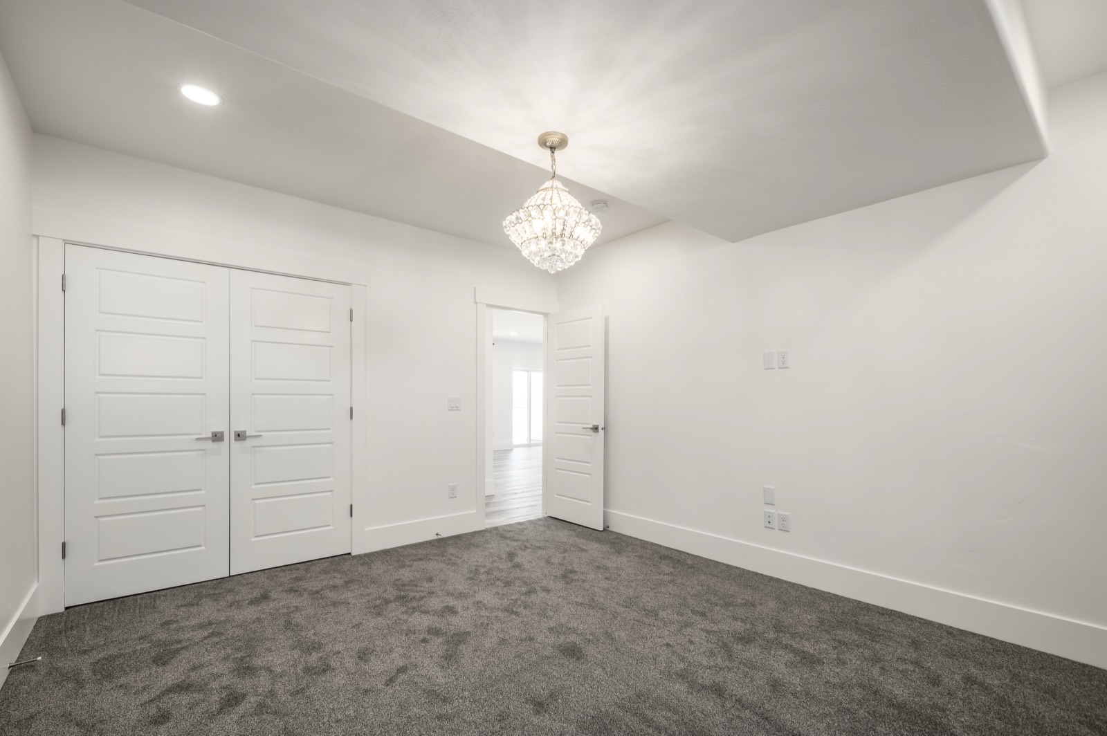 Finished basement bedroom with fresh white walls, plush carpet, and a chandelier