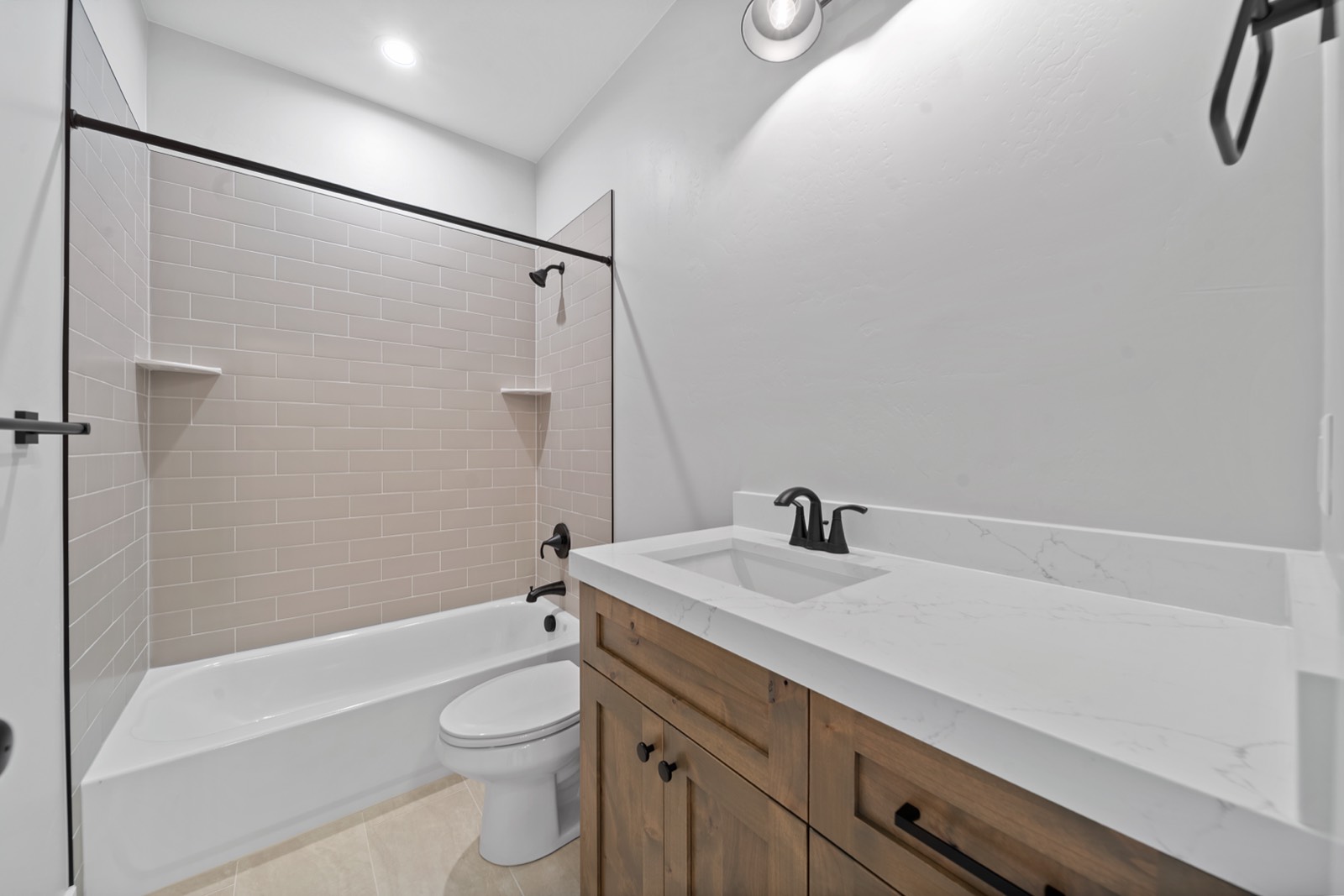 Remodeled bathroom with a tiled tub surround, quartz vanity, and matte black fixtures