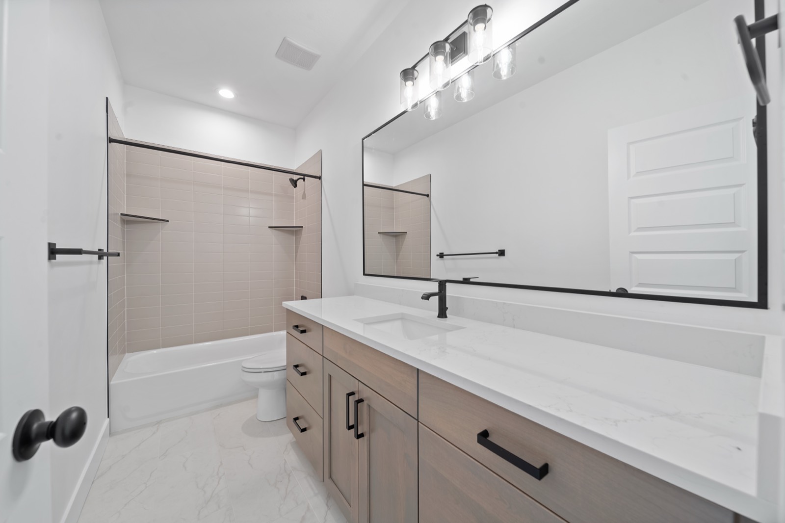 Remodeled bathroom with tile and a quartz vanity