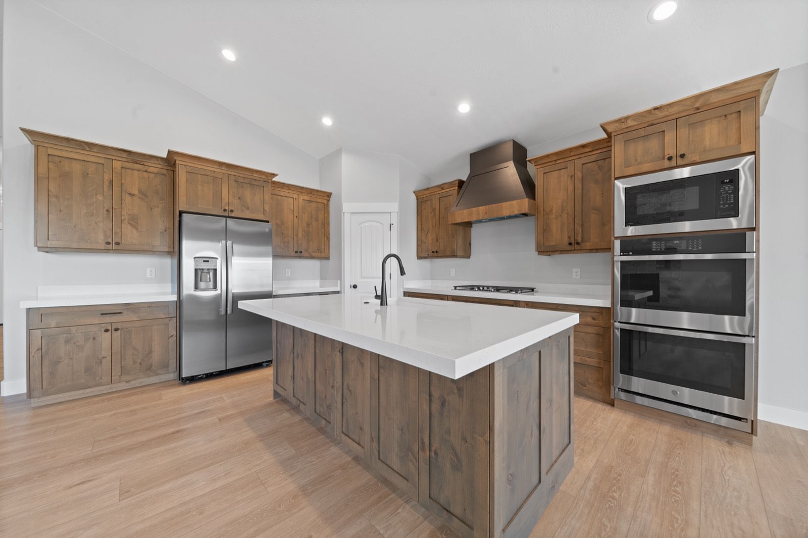 Remodeled kitchen with stained alder shaker cabinets, a white quartz island, and stainless appliances