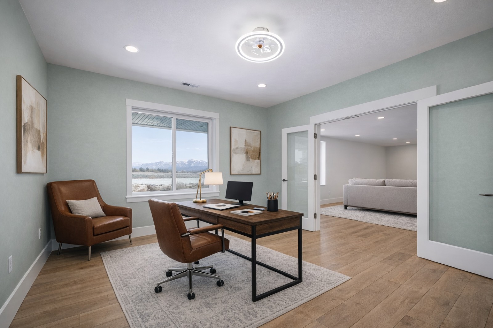 A finished home office with soft green walls, a leather chair, and a mountain view